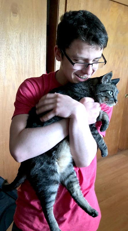 cat hugged by a teenage boy