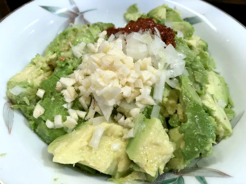 Guac ingredients in bowl. Have you ever wondered how to freeze guacamole for later use when avocados are plentiful, cheap, or in season? Here's how to make guacamole for freezing, as well as how to easily thaw it out for later during the lean times when avocados are over-ripe, under-ripe, or ridiculously expensive.