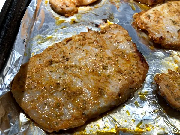 Pork chops on pan -- This flavorful 30 minute pork chops and zucchini recipe creates its own built-in side, making it an affordable weeknight dinner option for four. (The Greek yogurt sauce here really brings out the flavor in both the zucchini and the chops!) Broiled pork chops and zucchini are naturally low carb and gluten free.