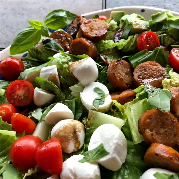 Plate of chopped tomato mozzarella chicken sausage salad