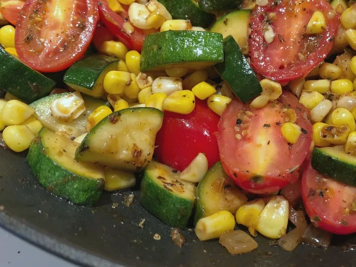 corn, zucchini, tomatoes in skillet