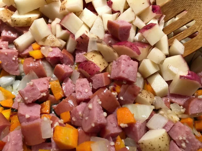 sausage, carrots, onions, and potatoes in a pot