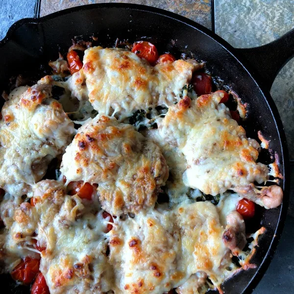 This naturally low carb & gluten free Caprese chicken + kale skillet recipe is the perfect easy one pan dinner solution if you're doing keto. (If you're not keto, a crusty loaf of bread or baguette pairs quite nicely!) | MashupMom.com caprese chicken and kale in a cast iron skillet