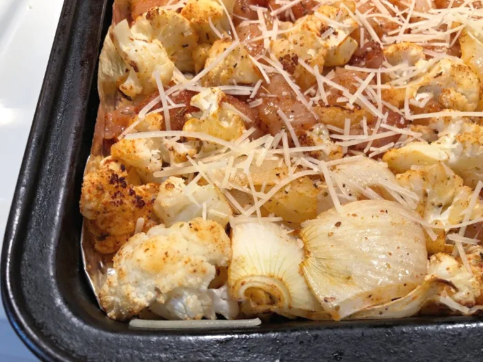 adding parmesan cheese to a sheet pan dinner