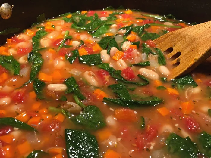big pot of vegetarian soup with white beans, carrots, and spinach
