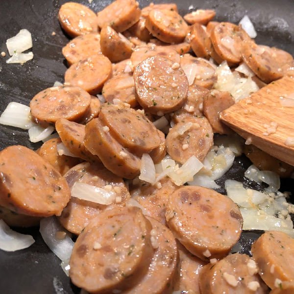 sauteing chicken sausage and onion in a pan