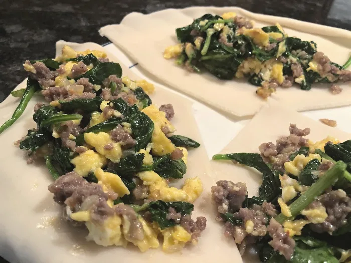adding filling to sausage, egg, & spinach hand pies
