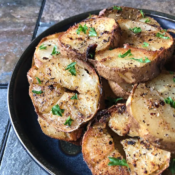 Pan fried potatoes on a plate, topped with parsley