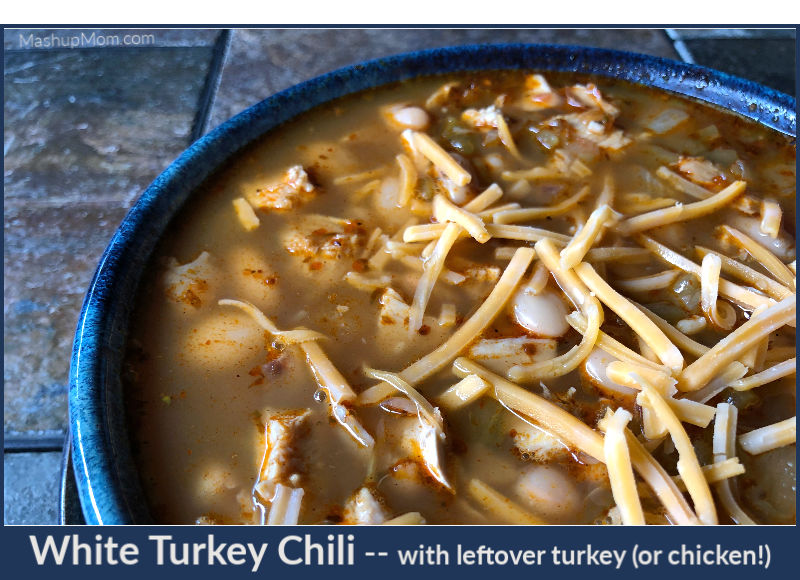 bowl of white turkey chili with shredded cheddar on top