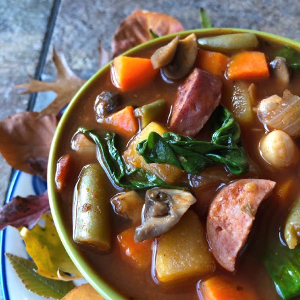 bowl of stew with smoked sausage veggies and acorn squash