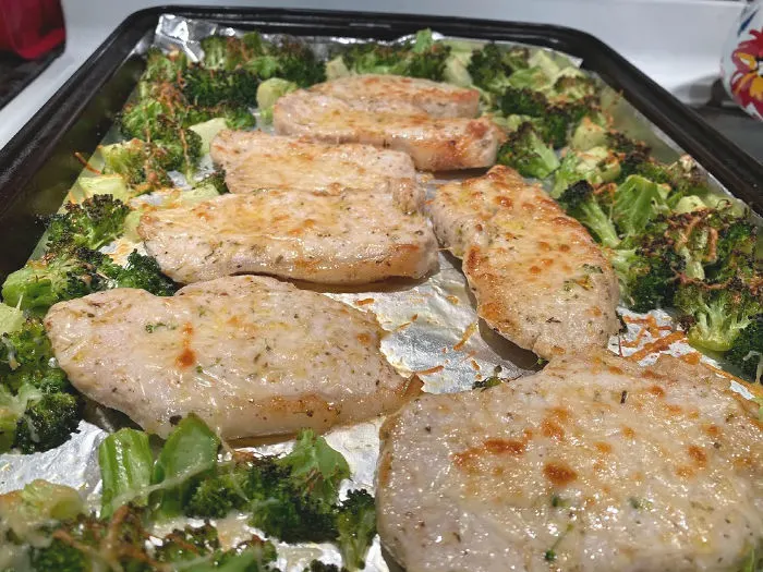 Finished pork chops and broccoli on a baking sheet