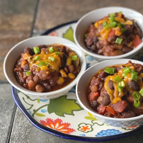 vegetarian chili with lentils and beans -- three bowls on a pretty plate