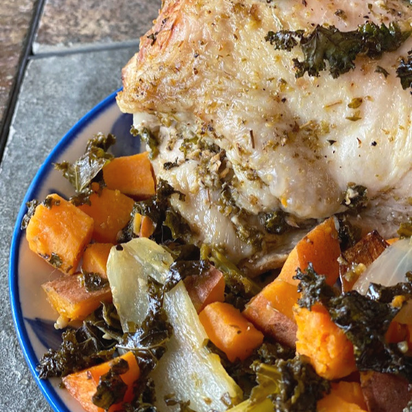 Plate of Greek chicken with sweet potatoes, kale, and onion