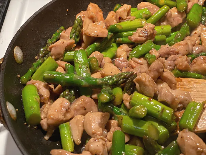 easy chicken asparagus stir fry in pan after sauce has thickened
