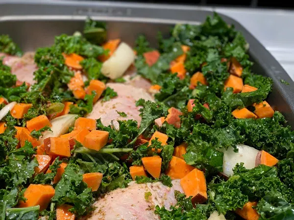 Arrange the kale and the sweet potatoes around the chicken in the pan