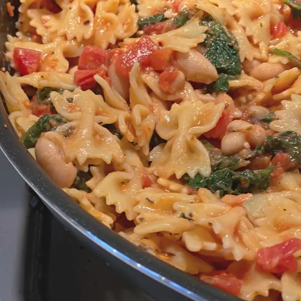 skillet of pasta with beans, tomatoes, and spinach