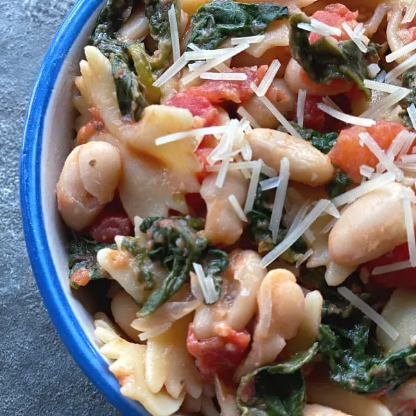bowl of pasta with spinach, white beans, and tomatoes