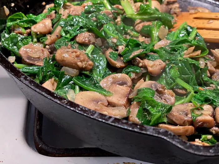 cooked spinach & mushrooms in a cast iron skillet