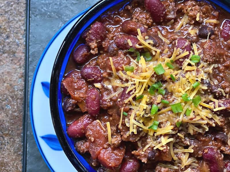 bowl of chili with cheese and green onions