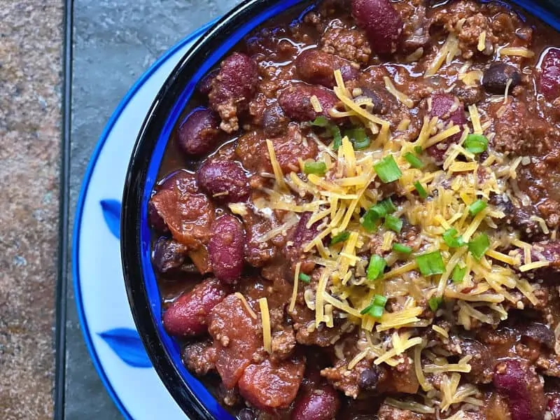 bowl of chili with cheese and green onion