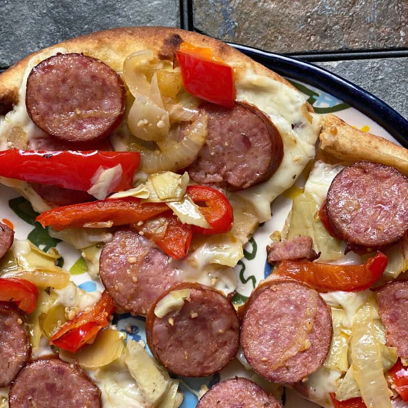 Naan pizza with sausage, peppers, onions, and artichoke