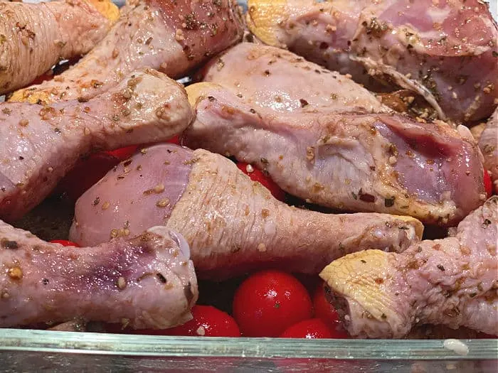 chicken drumsticks on top of tomatoes