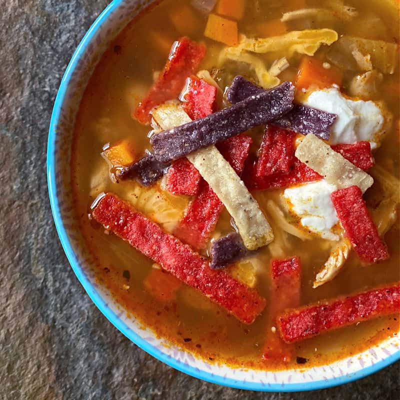 Bowl of chicken salsa verde soup topped with tortilla strips