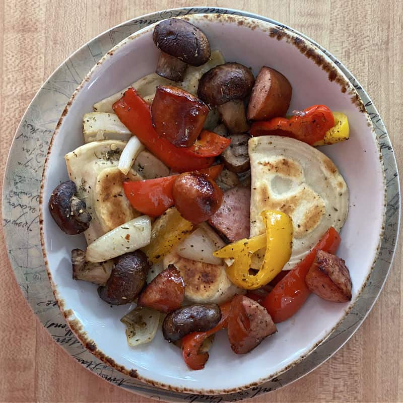 Bowl of sheet pan sausage peppers and pierogies