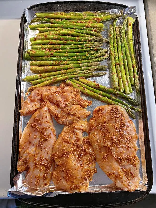 chicken and asparagus on a baking sheet