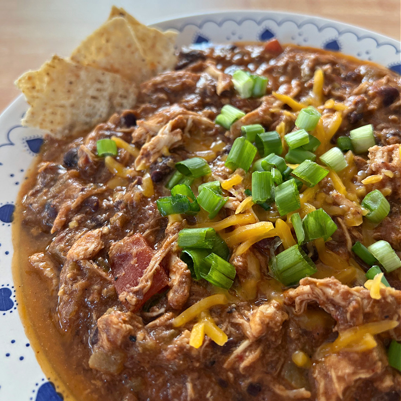 chicken chili with cheese, chips, and green onions