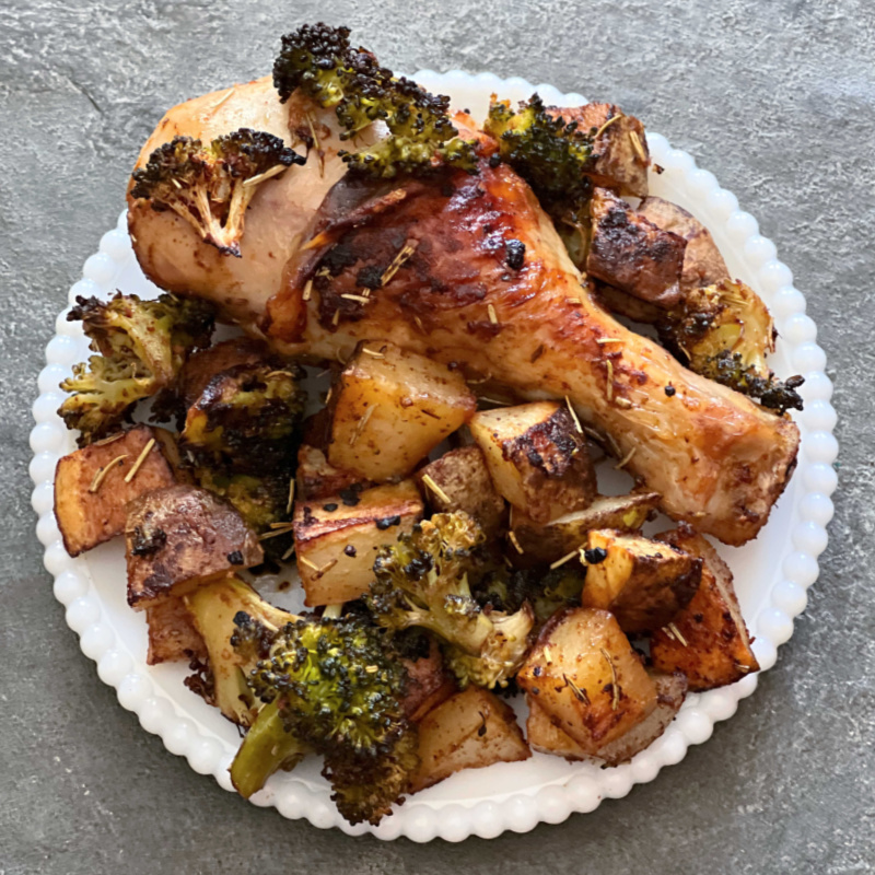 chicken drumstick, potatoes, and broccoli on a white plate