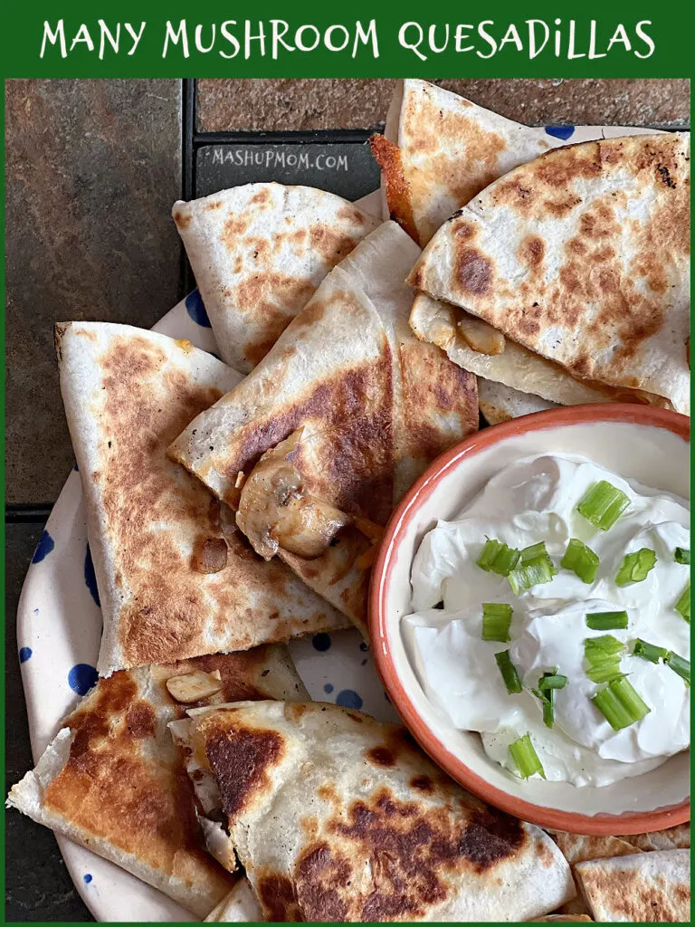 plate of quesadillas with a bowl of sour cream and green onions