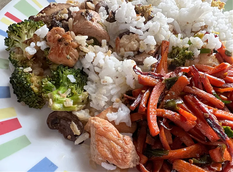 carrot and chicken stir fries with rice on a plate