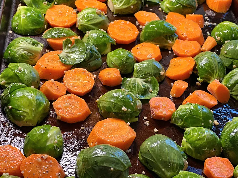 brussels and carrots with garlic on baking sheet