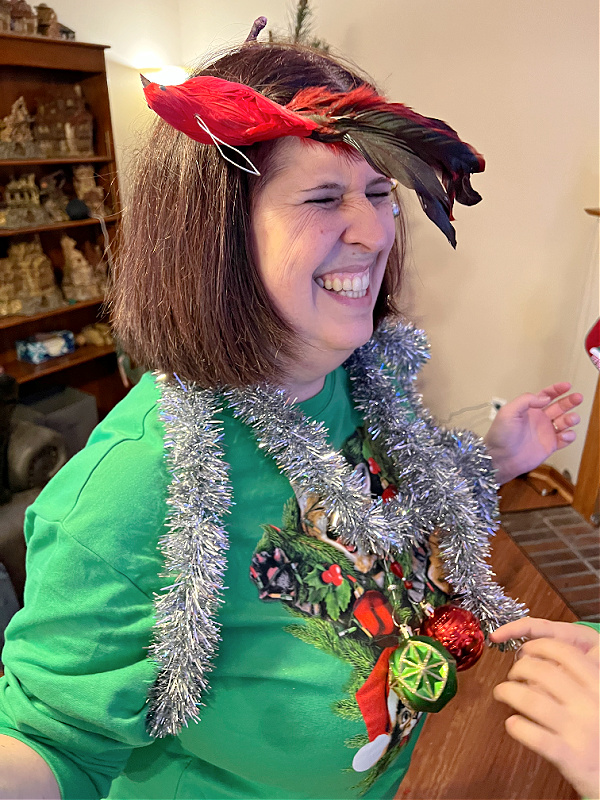 rachel in a crazy christmas sweater being decorated with tinsel