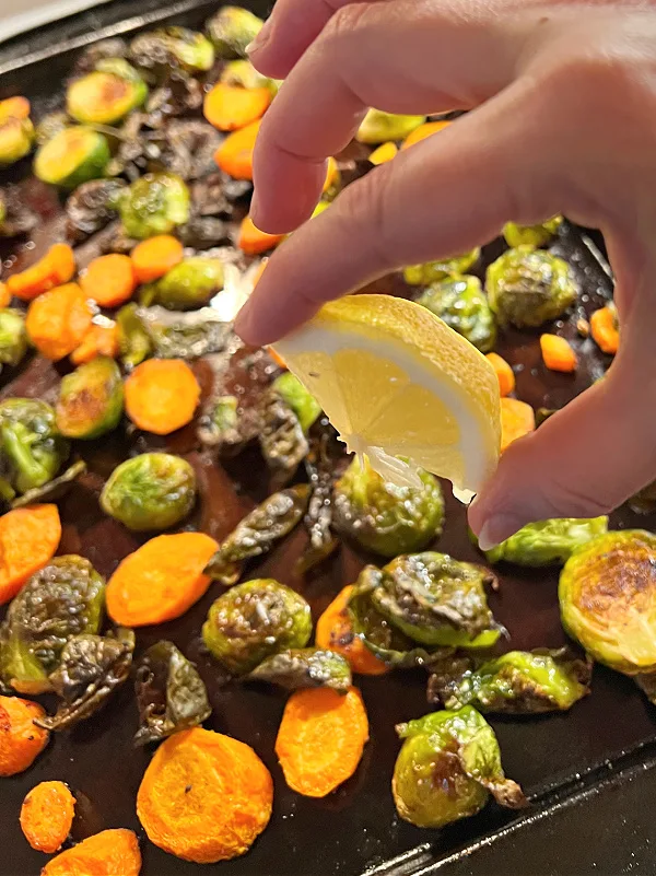 squeezing lemon juice on brussels and carrots