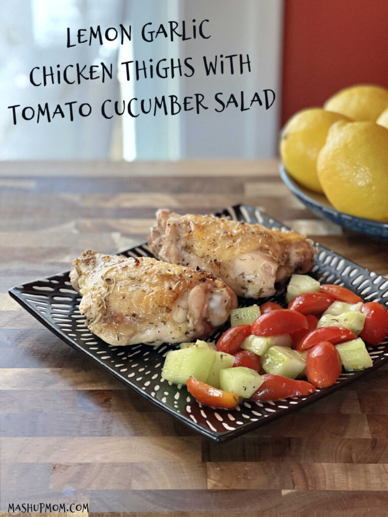 plate of chicken tomatoes and cucumbers on counter with lemons