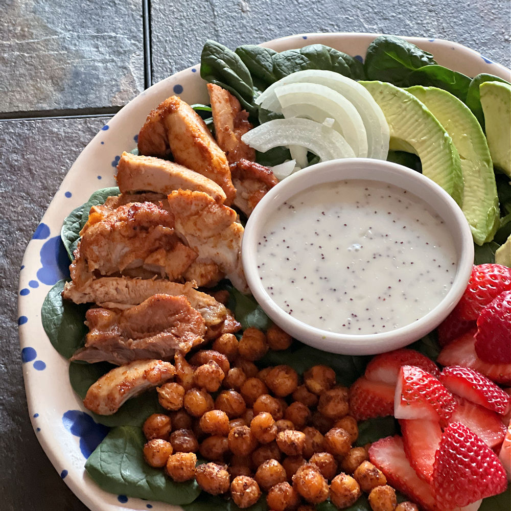 plate of spinach salad with strawberries, chicken, chickpeas