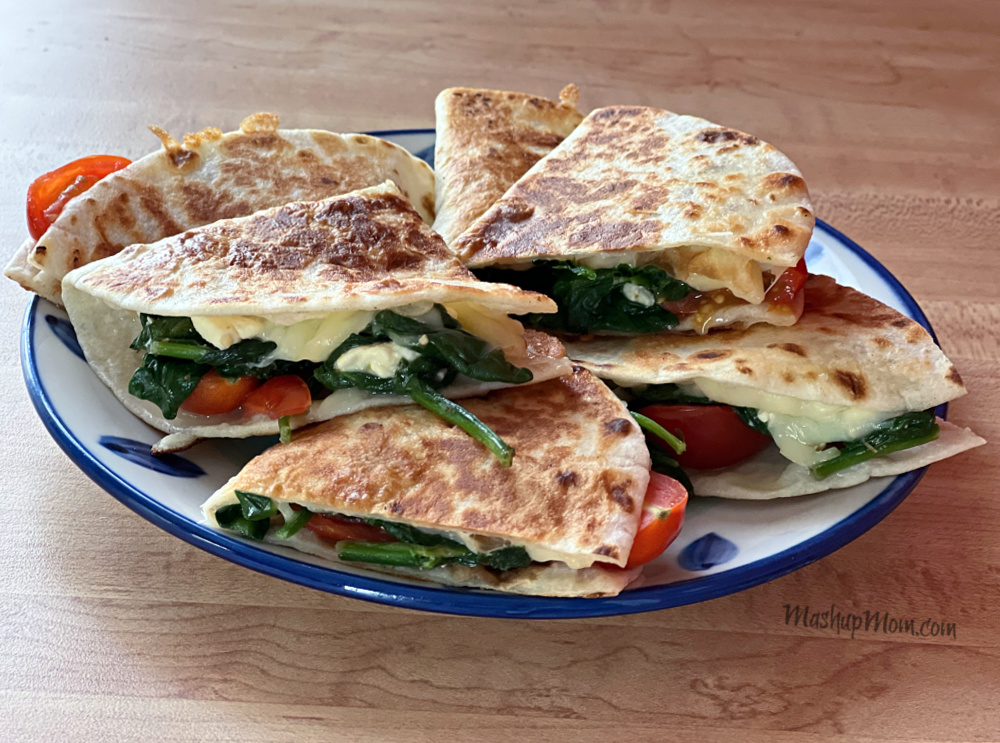 plate of quesadillas filled with spinach, tomatoes, feta, and mozzarella