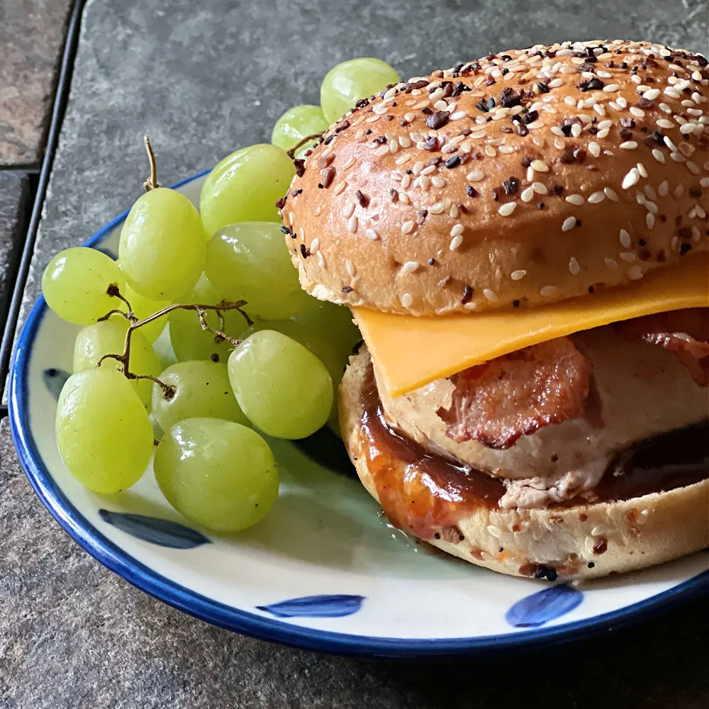 bbq bacon cheddar chicken sandwich on a plate with grapes