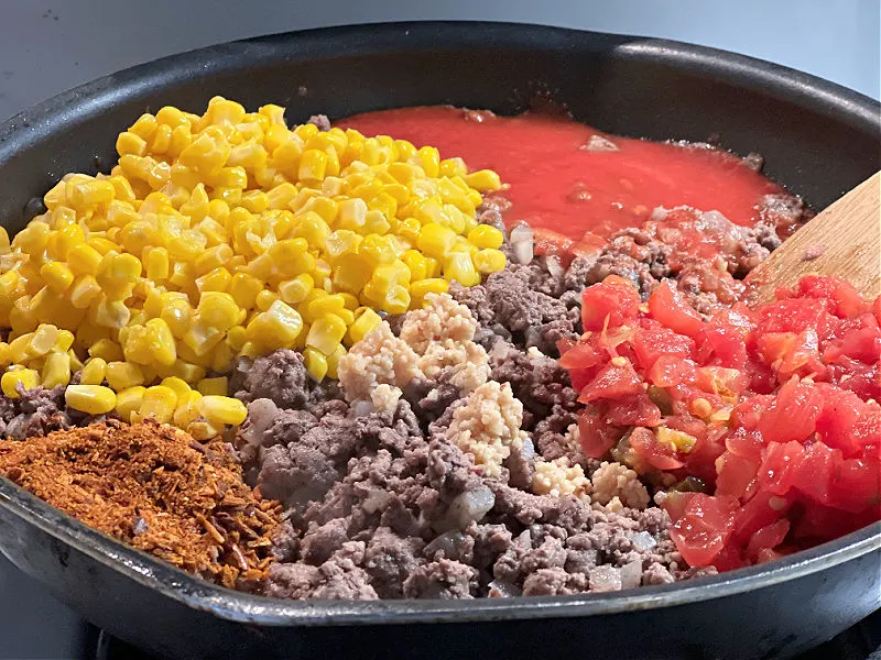add corn tomatoes and seasonings to the beef