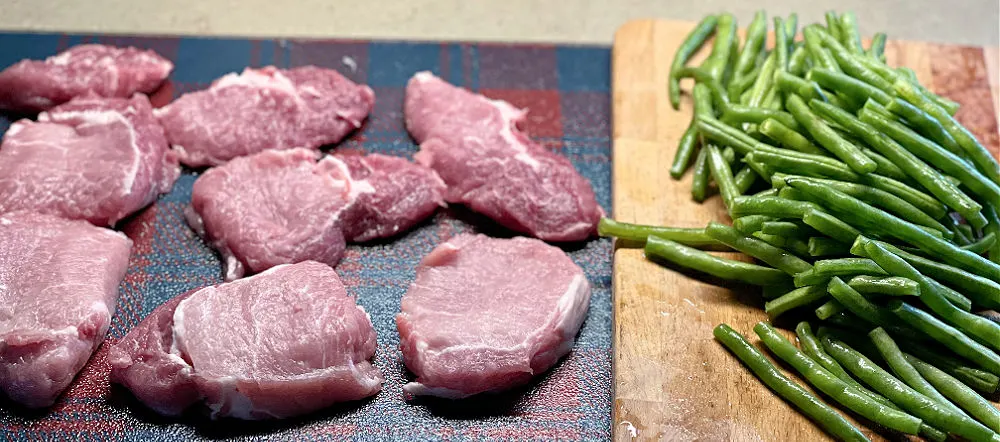 pork chops and green beans on a cutting board