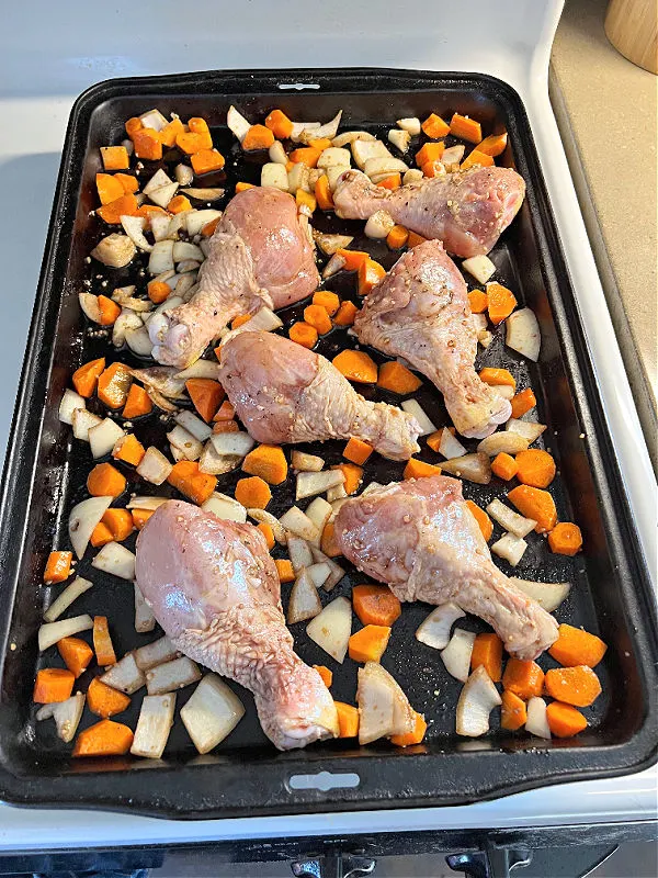 drumsticks, carrots, and onions on a sheet pan