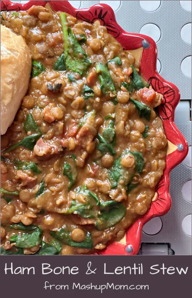 Ham bone & lentil stew with spinach & tomatoes, in a bowl with some baguette