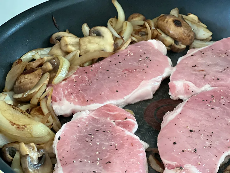 pork chops in the pan with mushrooms and onions