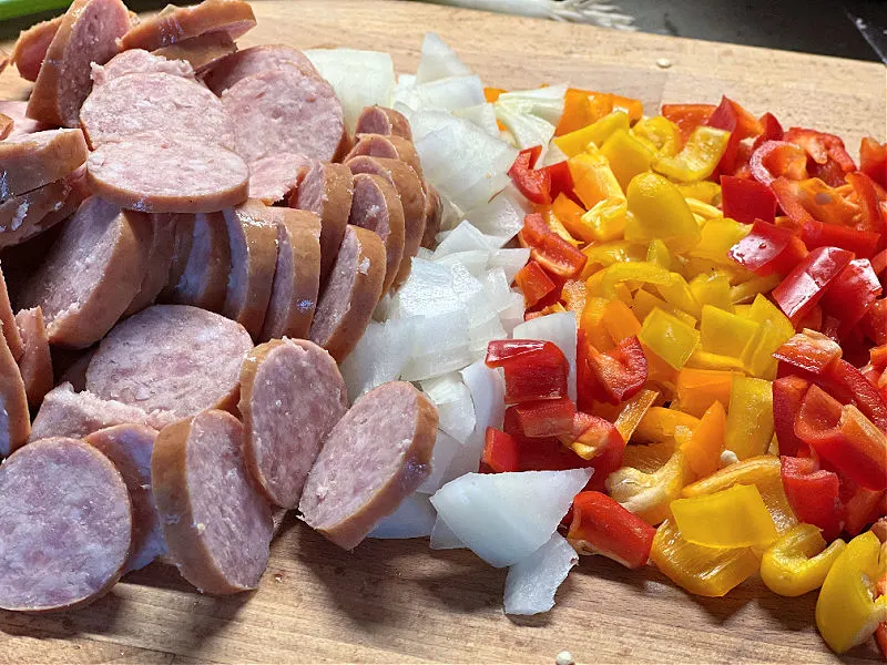 chopped sausage, peppers, and onions on a cutting board