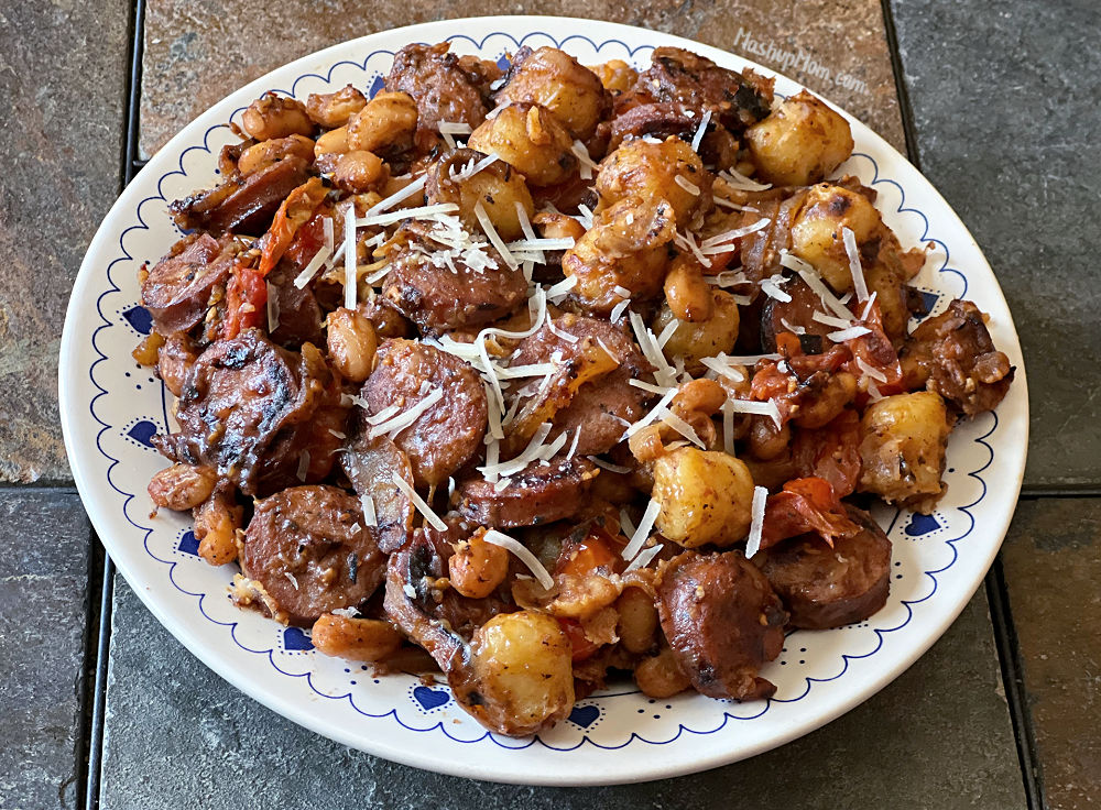 Plate of gnocchi with sausage, white beans, tomatoes, and topped with parmesan