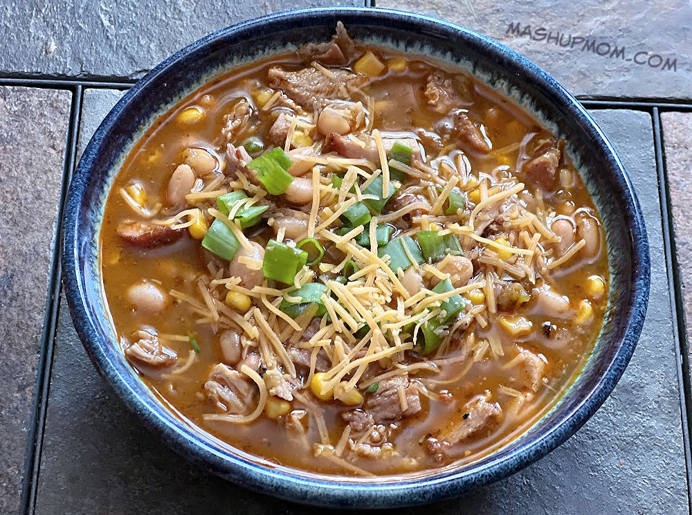 bowl of leftover pulled pork chili topped with cheese and green onions
