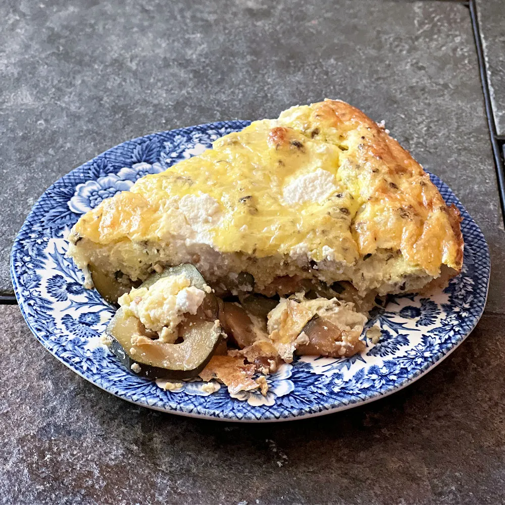 piece of zucchini ricotta frittata on a blue and white plate