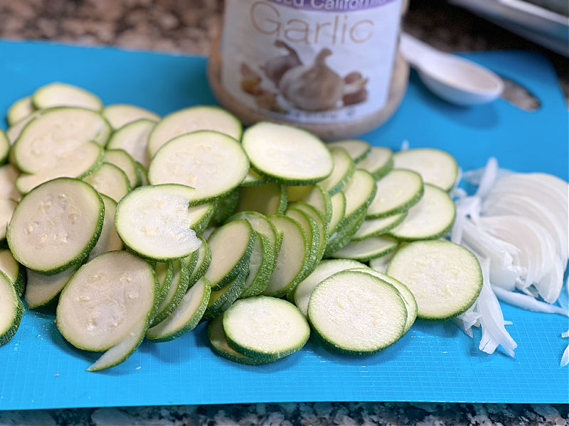 sliced zucchini and onion with a jar of minced garlic